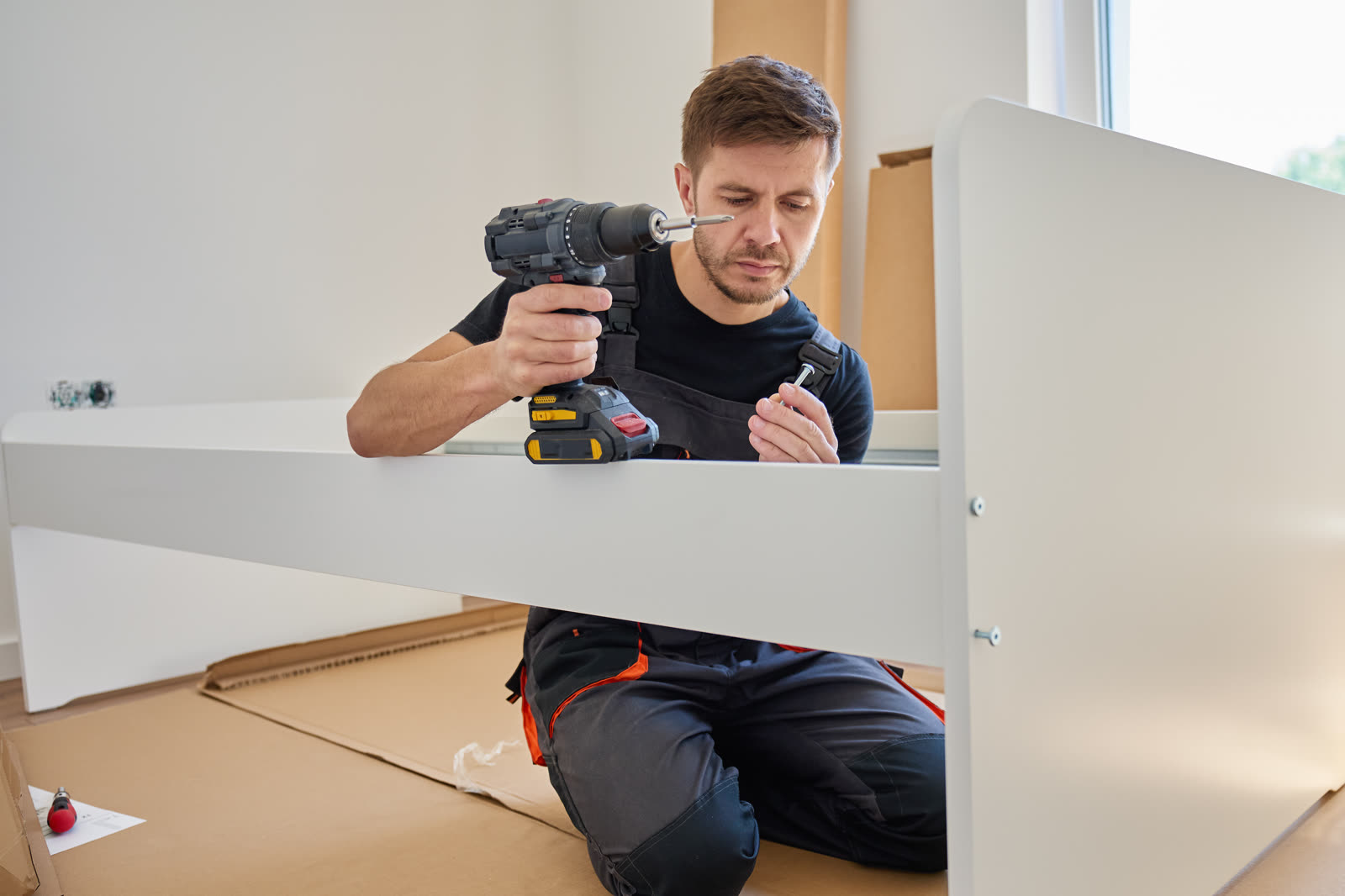 man using drill while assembling furniture at home — Furniture Assembly in Sarasota, FL