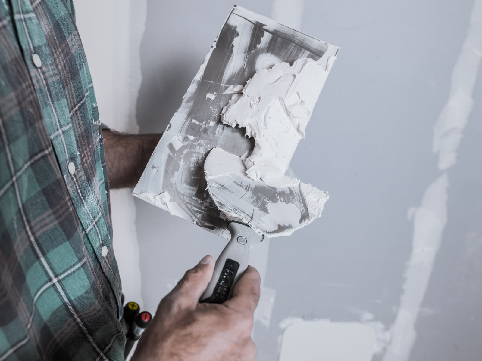 A mason prepares the putty with trowels to apply i — the kind of drywall repair & patching our vetted local pros handle in Sarasota, FL