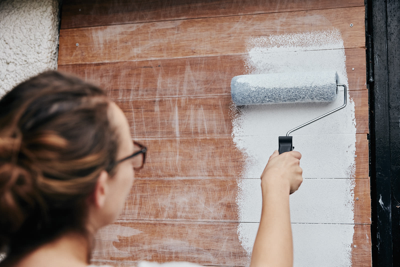 a woman using a paint roller painting wooden plan — Painting (Interior & Exterior) in Sarasota, FL