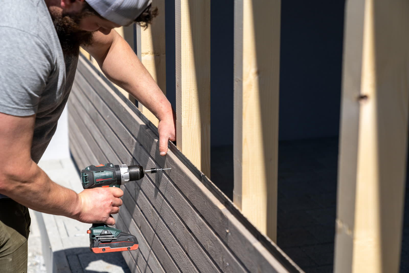 A tough construction worker applies wooden siding — the kind of pressure washing our vetted local pros handle in Sarasota, FL